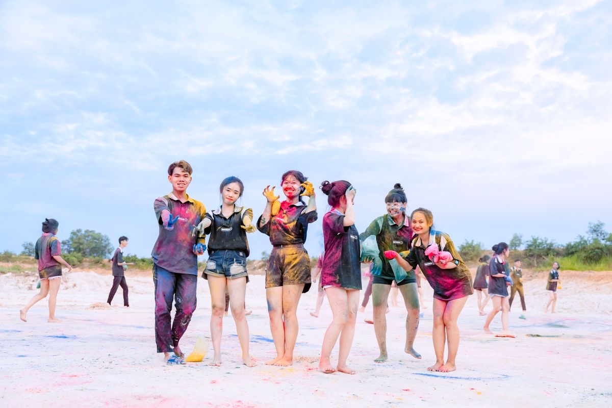 A group of friends laughing, covered in bright paint